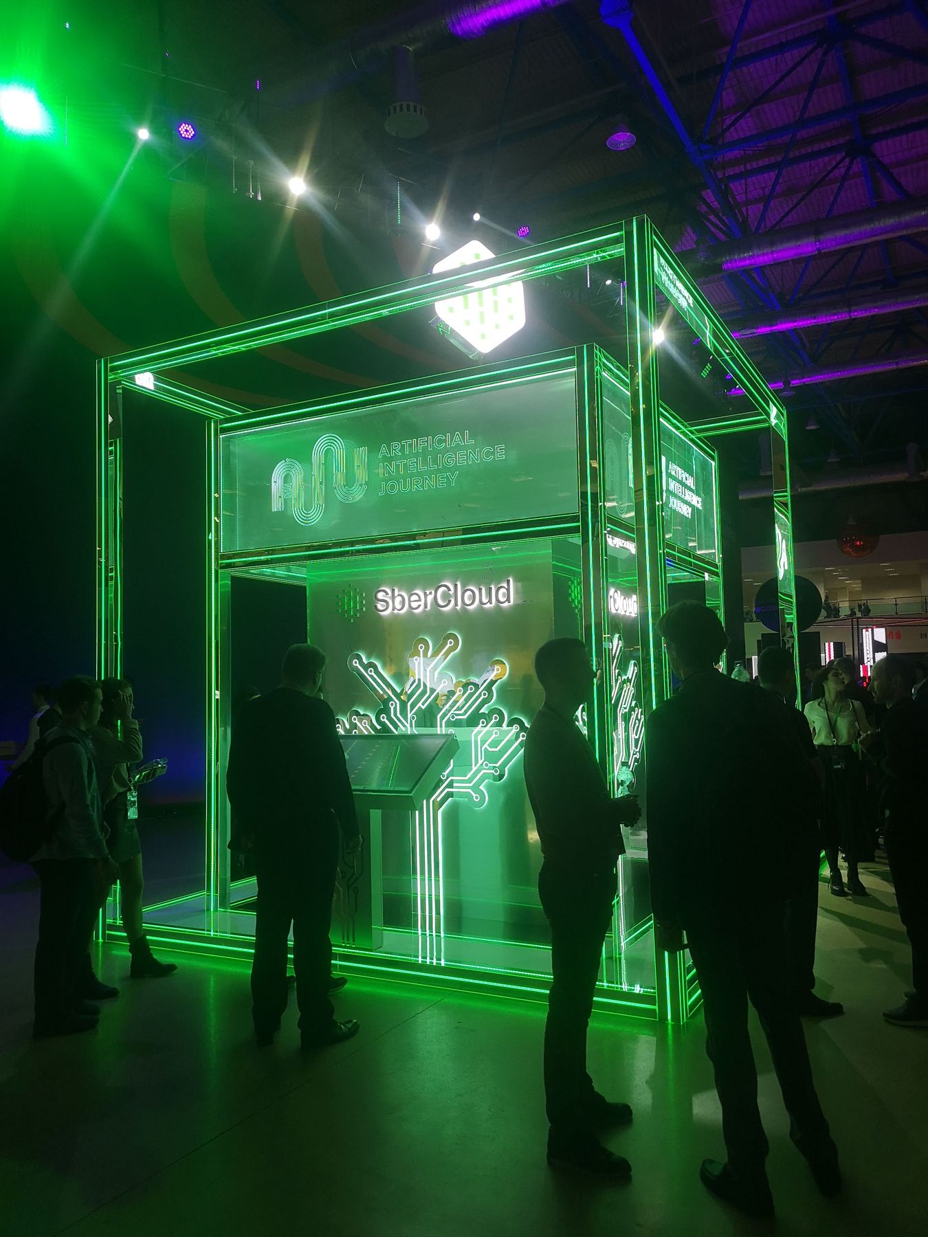 Стенд SberCloud на AI Journey: стеклянный куб с зелёной неоновой подсветкой, логотип AIJ, световое «дерево» из микросхем и тач-панель, 08.11.2019