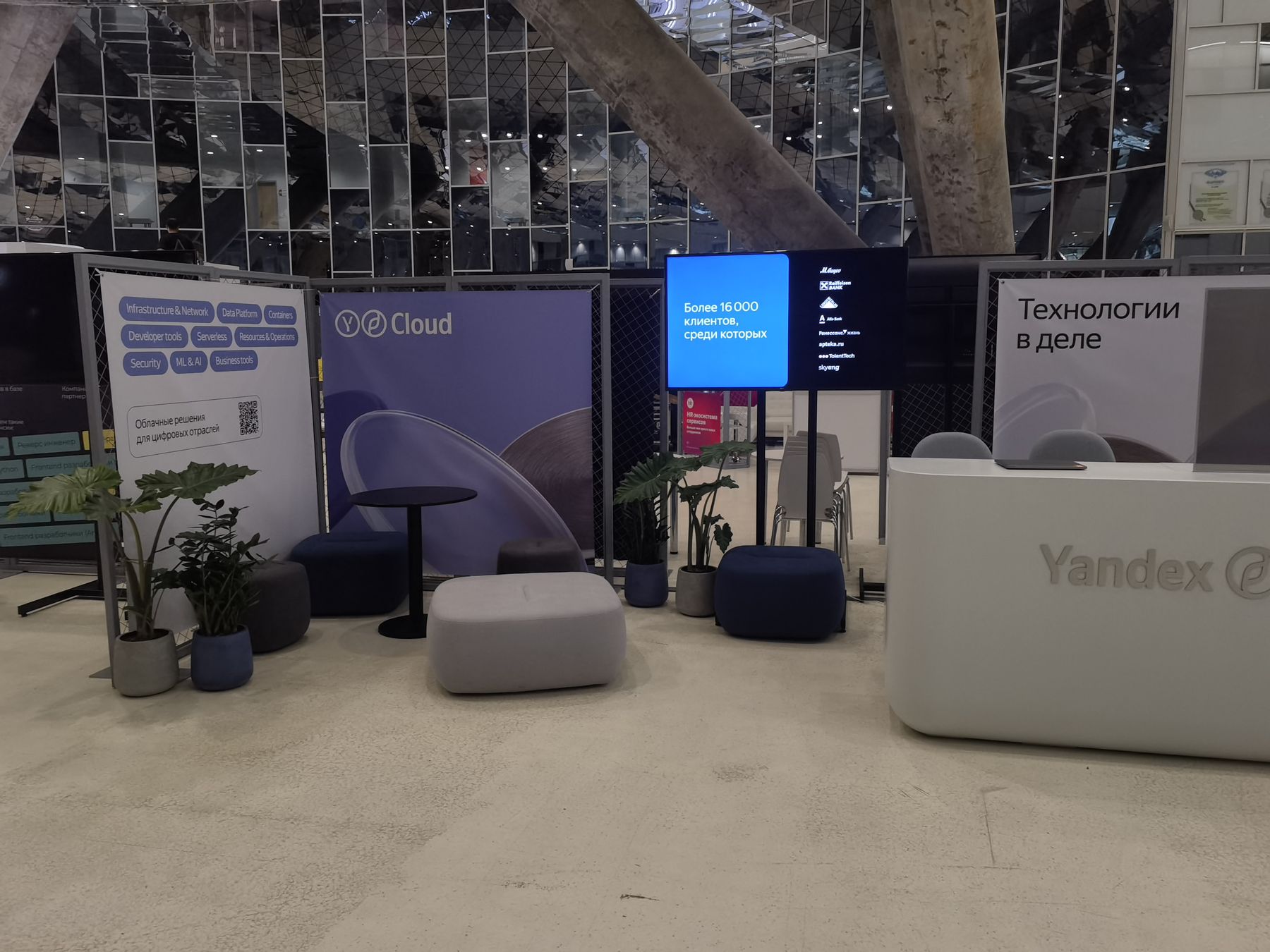 Стенд Yandex Cloud на Russian Tech Week: стойка с логотипом, баннер «Технологии в деле», экран, зона отдыха с растениями, 30.05.2022