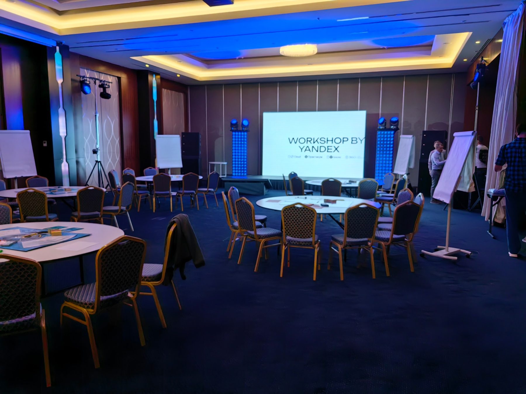 Зал с круглыми столами, флипчартами и экраном Workshop by Yandex