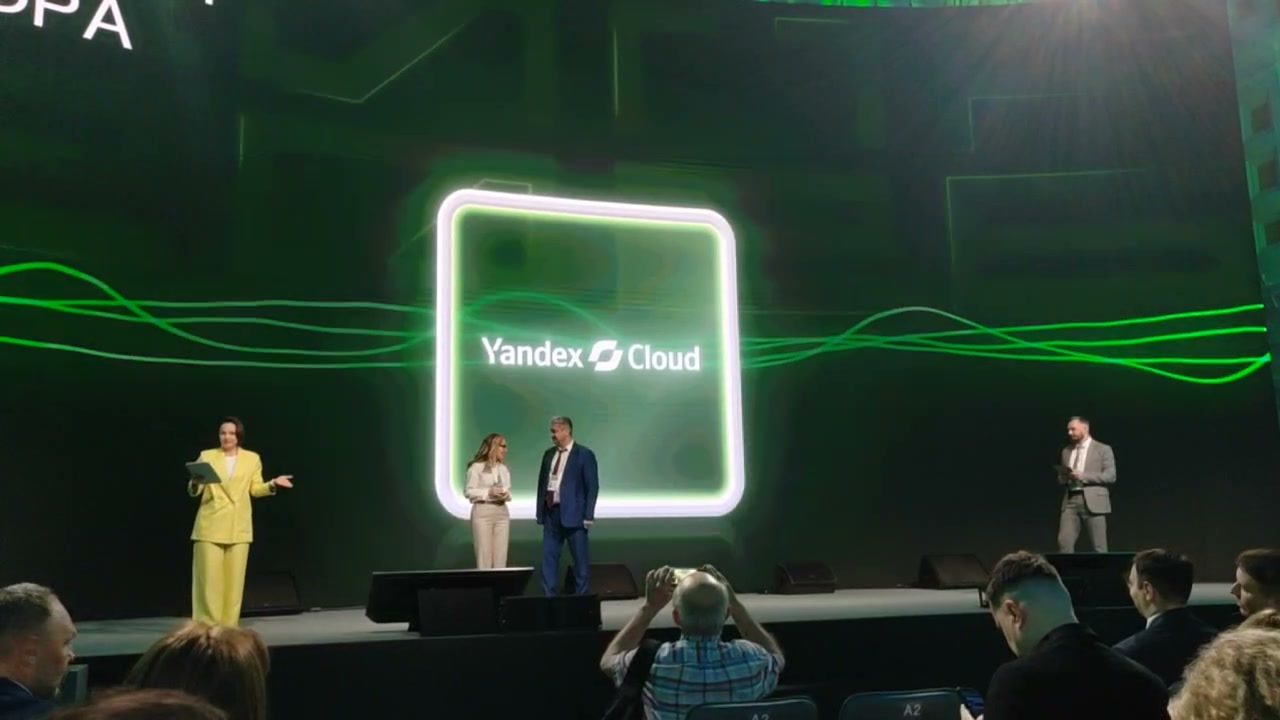 Сцена с зелёной световой графикой и логотипом Yandex Cloud